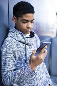 一个黑人使用手机青少年坐在楼梯上玩智能手机游戏美国黑人男孩正图片