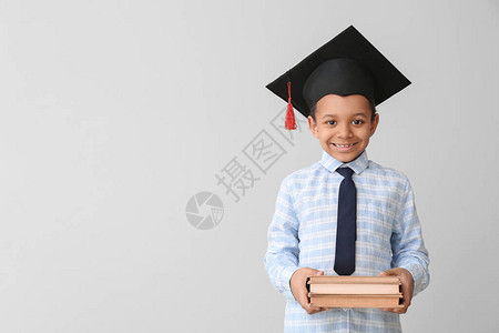 佩着毕业帽子和灰色背景书籍的非裔美国男孩非洲图片