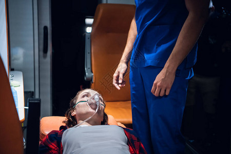 一个女人躺在担架上戴着氧气面罩看着穿蓝色制图片