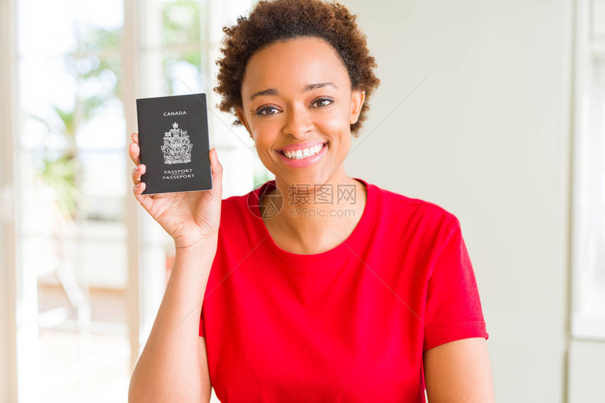 持有加拿大护照面脸笑站立和微笑的年轻非洲美妇女满怀自信的微笑图片