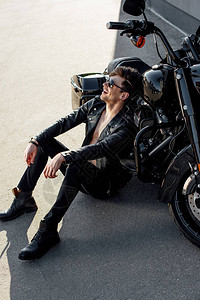 年轻男人坐在摩托车旁边的地上图片