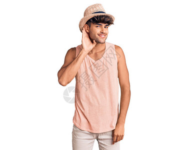戴着暑假帽子的年轻西班牙男子笑着双耳听闻谣言或八卦图片