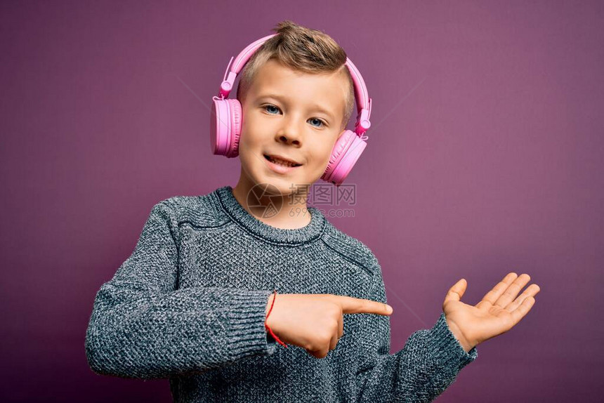 年轻的白人小孩戴着耳机在紫色背景下听音乐图片