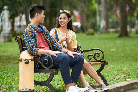 快乐的年轻约会情侣坐在公园的长图片
