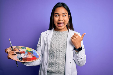 年轻的亚洲艺术家女孩用画笔和调色板绘画图片
