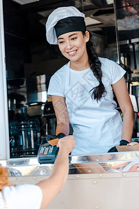以信用卡付账的客户面前笑着微笑的亚裔妇女有图片