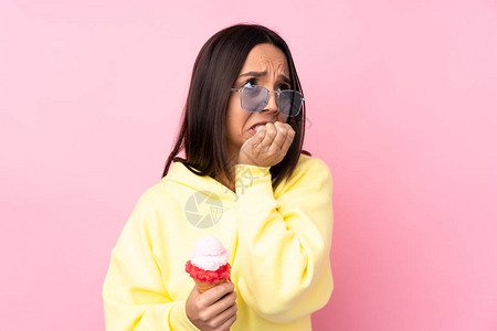 小黑发女孩拿着玉米饼冰淇淋在孤立的粉红背景下紧张图片