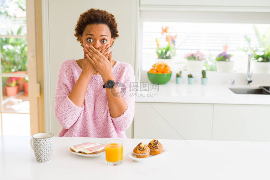 早上在家中吃早餐的年轻美国女因错误而用双手遮住嘴图片