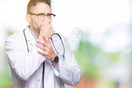 身处孤立背景的英俊年轻医生男子闻到一些臭味恶心无法忍受的气味图片