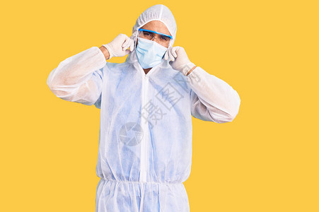 身穿医生保护科罗纳制服和用指头遮住耳朵的医学面具图片
