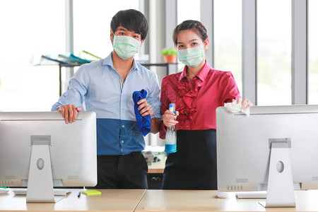 同事员工佩戴卫生口罩清洁和消毒办公工具和设备图片
