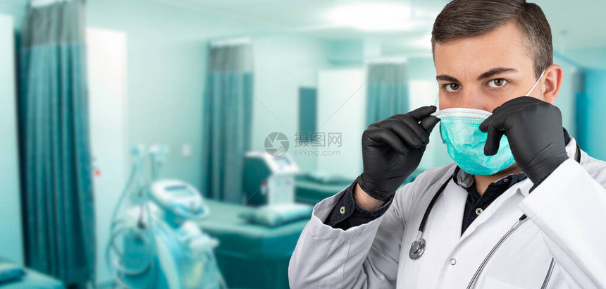 白人男子身穿白色整体或用听诊器在脖子上戴黑色手套擦洗戴上防护面罩背景是医院病床左图片