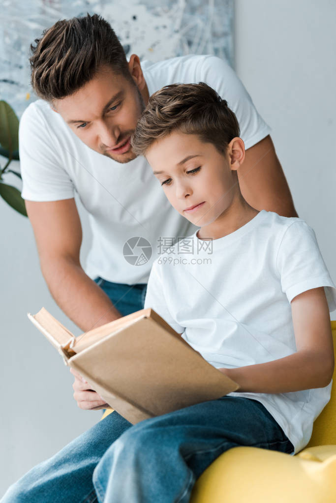 父亲在沙发上坐着时站在儿子旁边拿图片