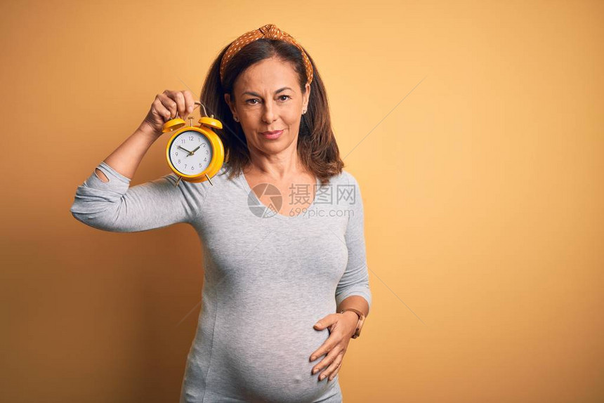 怀孕时预产期婴儿的中年孕妇持闹钟图片