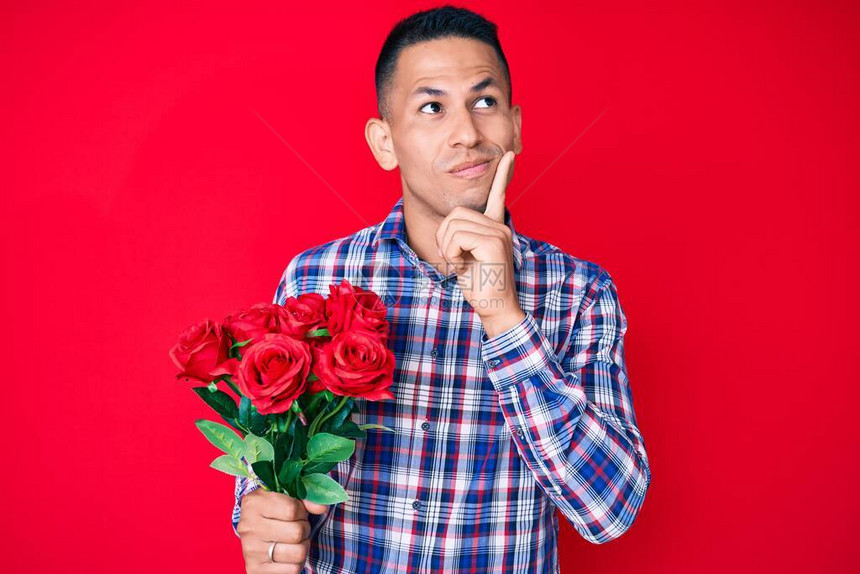 年轻英俊的拉丁男子拿着鲜花严肃面对正脸图片