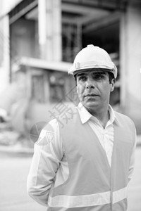 黑白建筑工地的英俊波斯男子建筑工人的肖像图片