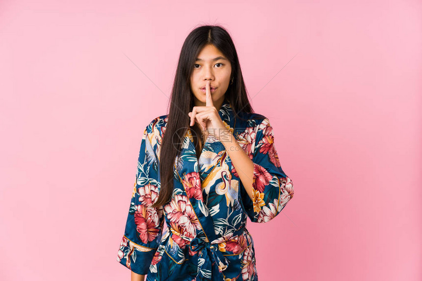 穿着和服睡衣的年轻的亚洲女人保守秘密或图片