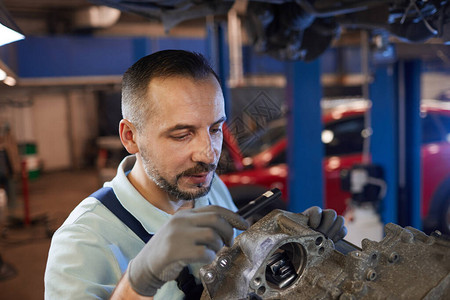 汽车修理车间复印空间内留胡子的汽车机械工检查变速图片