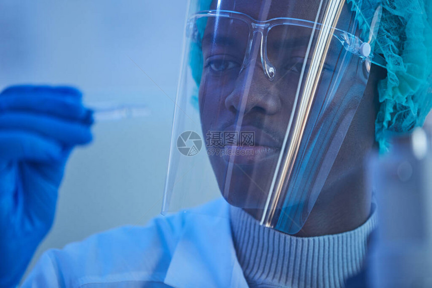身戴保护面具检查手中药剂的非洲青年男子近身图片