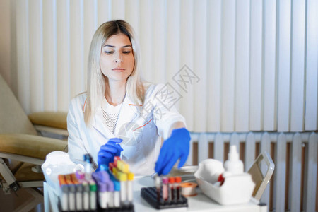 护士在实验室进行验血一位身穿医用白大褂蓝色乳胶手套的金发女子正在检图片