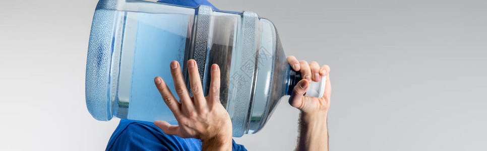 携带肩上瓶装水的快递者侧面视线夹在灰色背景图片