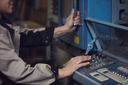生产工厂操作机器时无法辨认的女工转动把手的特图片