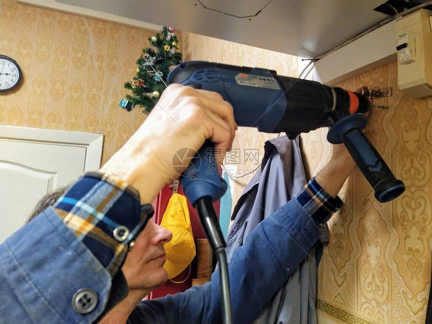 欧洲成人工在车间用电钻挂衣架的图片