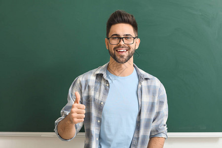 男老师在教室的黑板旁竖起大拇指图片