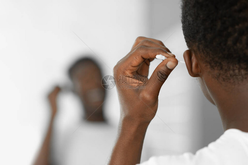 黑人男子用棉签站在家里的浴室里清洁耳朵清洁耳朵和安全去除耳垢日常卫生和自我护理裁剪后视图图片