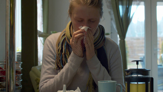 感冒和鼻塞的年轻女子在餐巾纸上打鼻子保健和图片