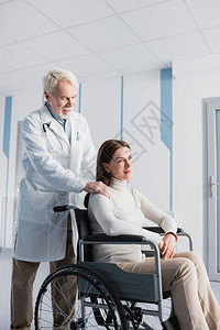 高级医生触摸残疾病人的肩部轮椅残疾图片