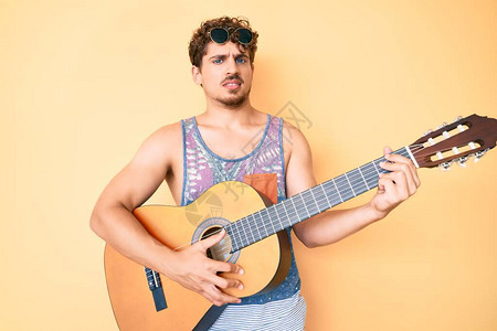 有卷发的年轻caucasian男子弹着古典吉他没有线索和困惑的表达方式图片