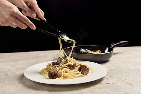 女人将美味的意大利意大利意面和海鲜放在盘子上的美食完图片