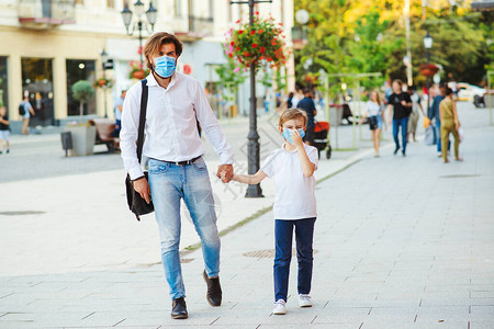 时尚的父子在隔离期间走在街上面罩以保护免受冠状的侵害安全童年父亲带着孩子在城里戴着医用口罩家长带着背景图片