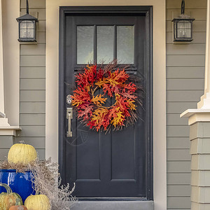 一栋房子的蓝色前门上挂着五颜六色的秋花环图片