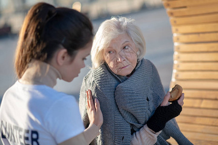 不忘感恩支持无家可归者黑发善良的志愿者在街上支持老年无背景