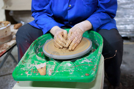 陶艺第一课的新学生试图在陶器轮子上用粘土制成产品报告手背景图片