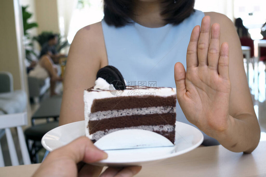 其中一位保健女童用一只手推着一块巧克力蛋糕拒绝吃含有外发食品的食物但图片