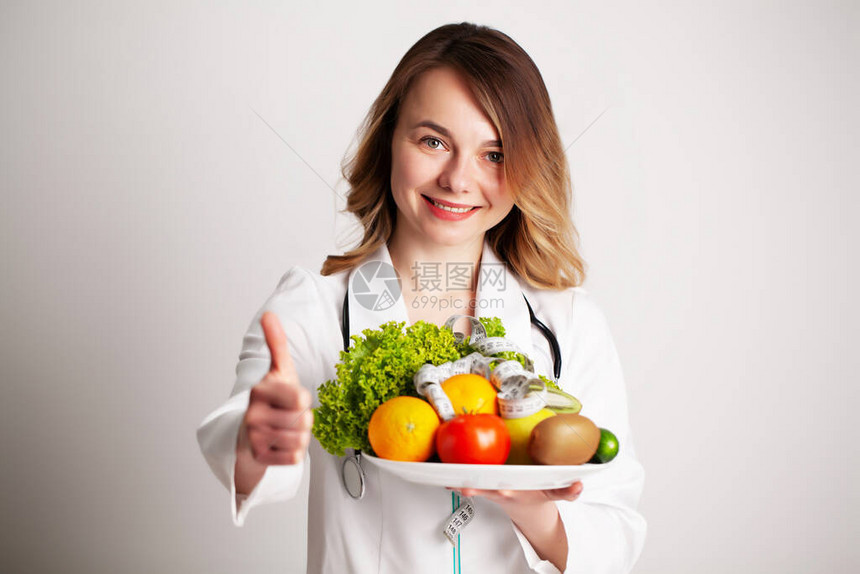 一位年轻的营养学家在磋商室将新鲜蔬菜和水果放在盘子上图片