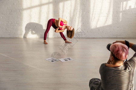 赤脚在摄影师附近做瑜伽锻炼的体育妇女有图片