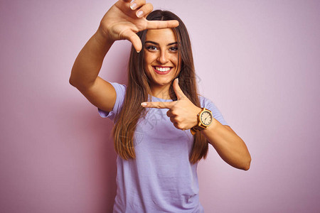 身穿临时T恤的年轻美女站在孤立的粉红色背景上微笑地用手和指搭架图片
