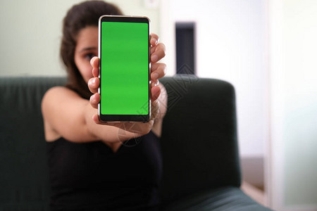 年轻的caucasian女人躲在绿色屏幕的图片