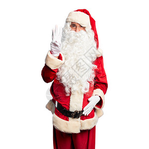 身着圣诞老人服装和胡子的中年英俊男子站着露脸用三号手指举起手满怀自信背景图片