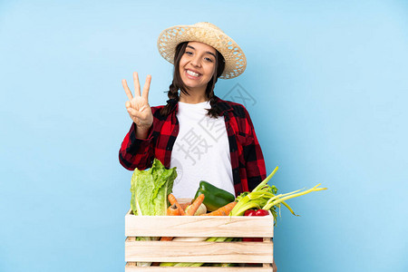 年轻农妇在木篮子里盛着新鲜蔬菜的年轻女农民快乐地背景图片