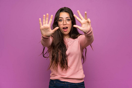 十几岁的女孩在紫色的墙上用手指数着九图片