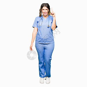 身穿医疗制服的年轻成年女医生与成功的想法对着指图片