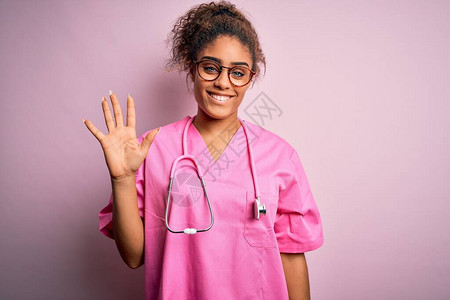 身穿医疗制服和听诊器的非裔美国护士女孩在粉红色背景展示时图片
