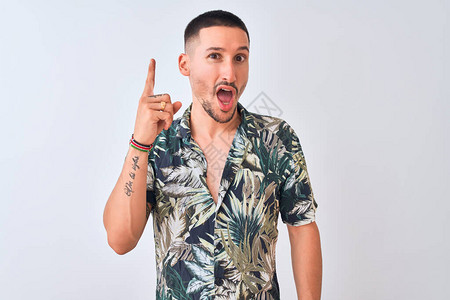 英俊的年轻人穿着夏威夷暑假衬衫身穿孤立的背景与成功的点子指手画脚图片