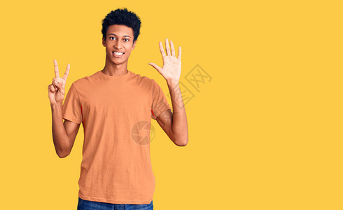 身穿散装衣的年轻非洲男子带着7号指着手指笑着满怀自信和快乐地笑起来图片
