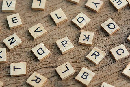 木质背景上凸版木型印刷块的背景字母随机字母和黑色墨水染图片